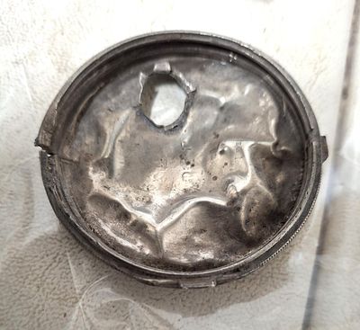 Antique silver back plate for a pocket watch with a bullet hole through it - local metal 