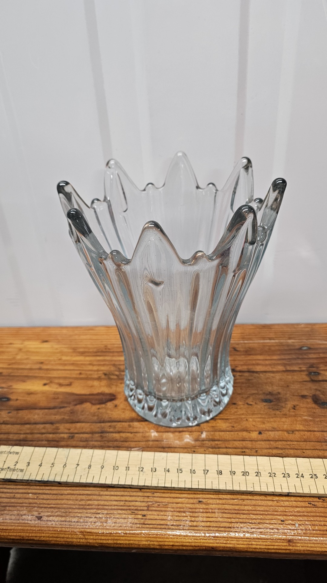 A clear pressed glass flared vase with a serrated star rim