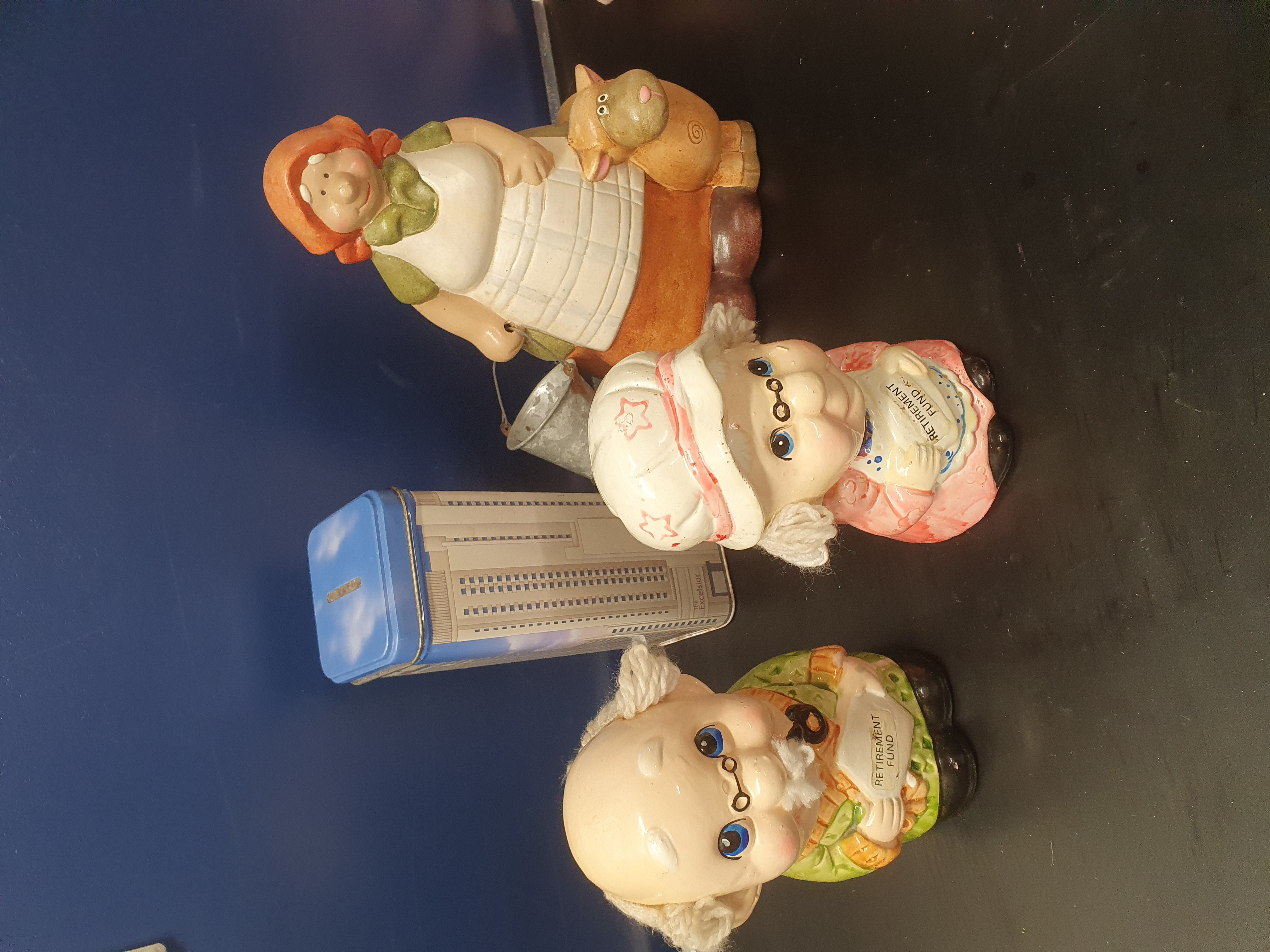 An Assortment of Vintage Ceramic Figural Money Boxes and a Lithographed Souvenir Tin