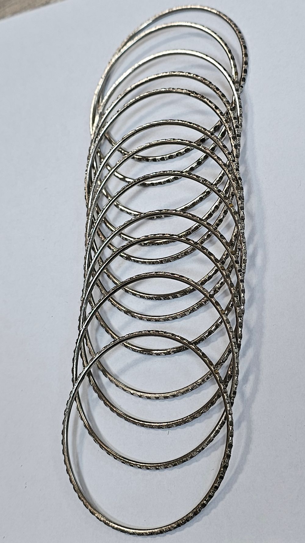 Lot 253: Set of Twelve Silver Tone Diamond Cut Textured Metal Bangles - Good Condition