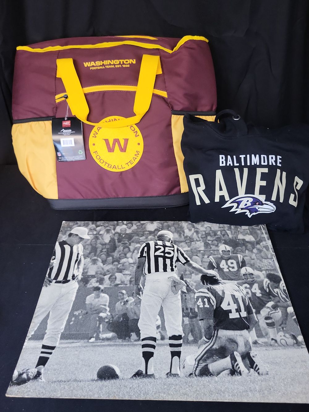 Lot 280: I01766 | A Trio of NFL Memorabilia Including a Washington Football Team Cooler Bag, Baltimore Ravens Hoodie, and Vintage Baltimore Colts Photographic Print
