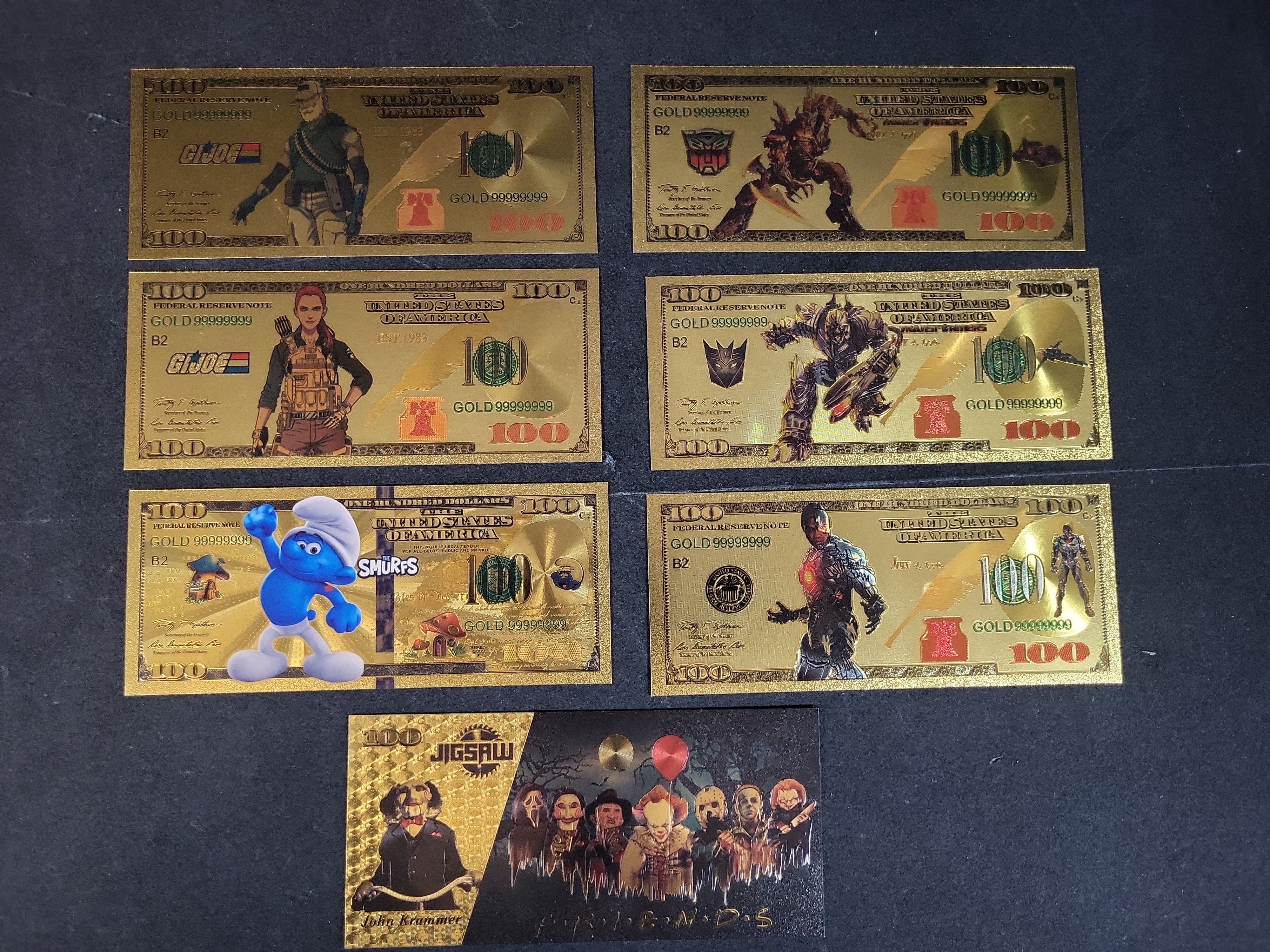 I03653 | Seven Novelty Gold Foil Banknotes Featuring G.I. Joe, Transformers, The Smurfs, and Cinematic Characters