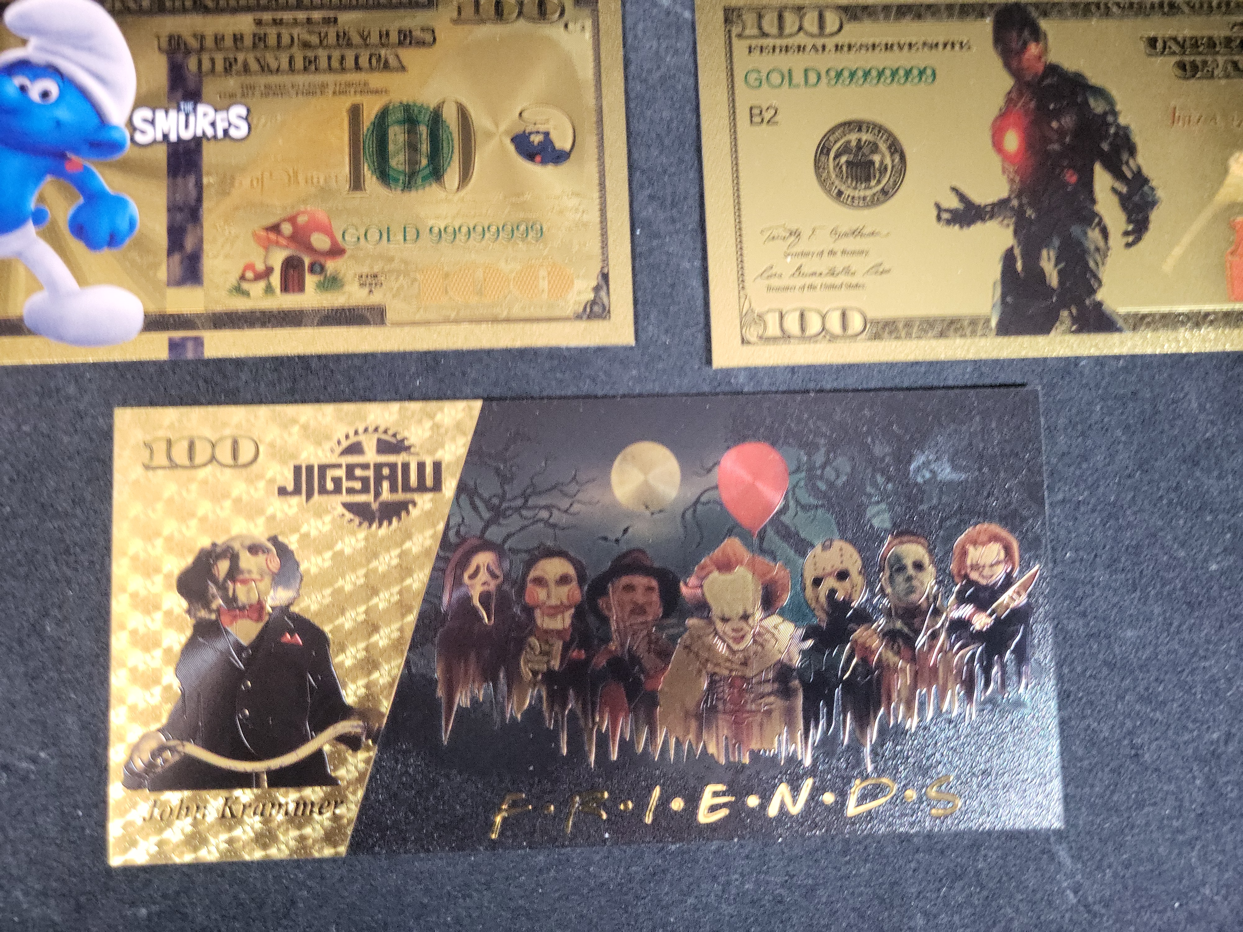 I03653 | Seven Novelty Gold Foil Banknotes Featuring G.I. Joe, Transformers, The Smurfs, and Cinematic Characters