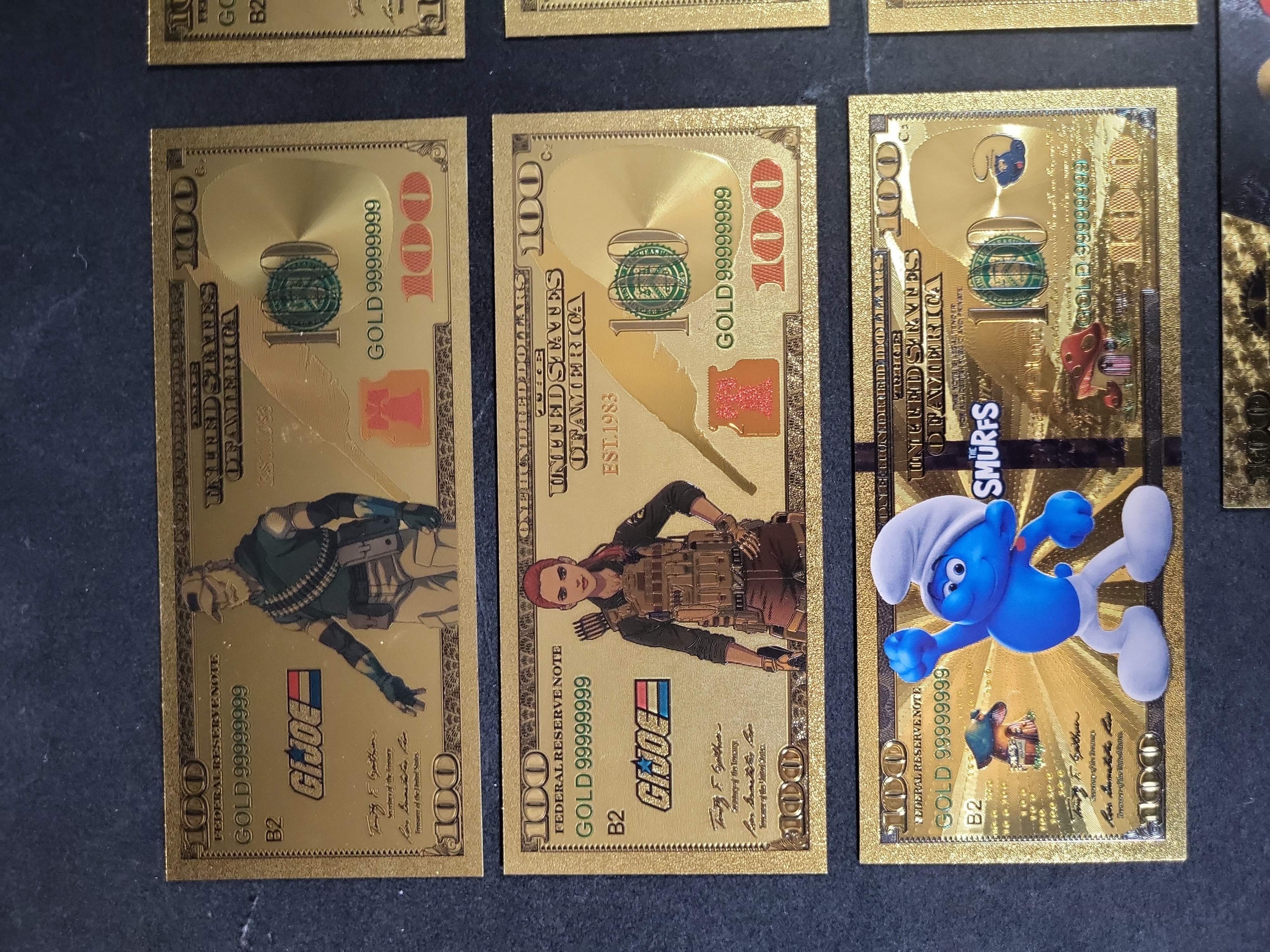 I03653 | Seven Novelty Gold Foil Banknotes Featuring G.I. Joe, Transformers, The Smurfs, and Cinematic Characters