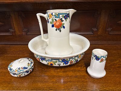 An early 20th century four piece toilet set having floral transfer decoration, damage to lid of 