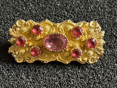 A 19th century gilt metal or pinchbeck brooch, inset with stones 12 gm
