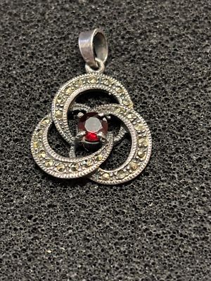 A silver and marcasite pendant with red stone stamped 925