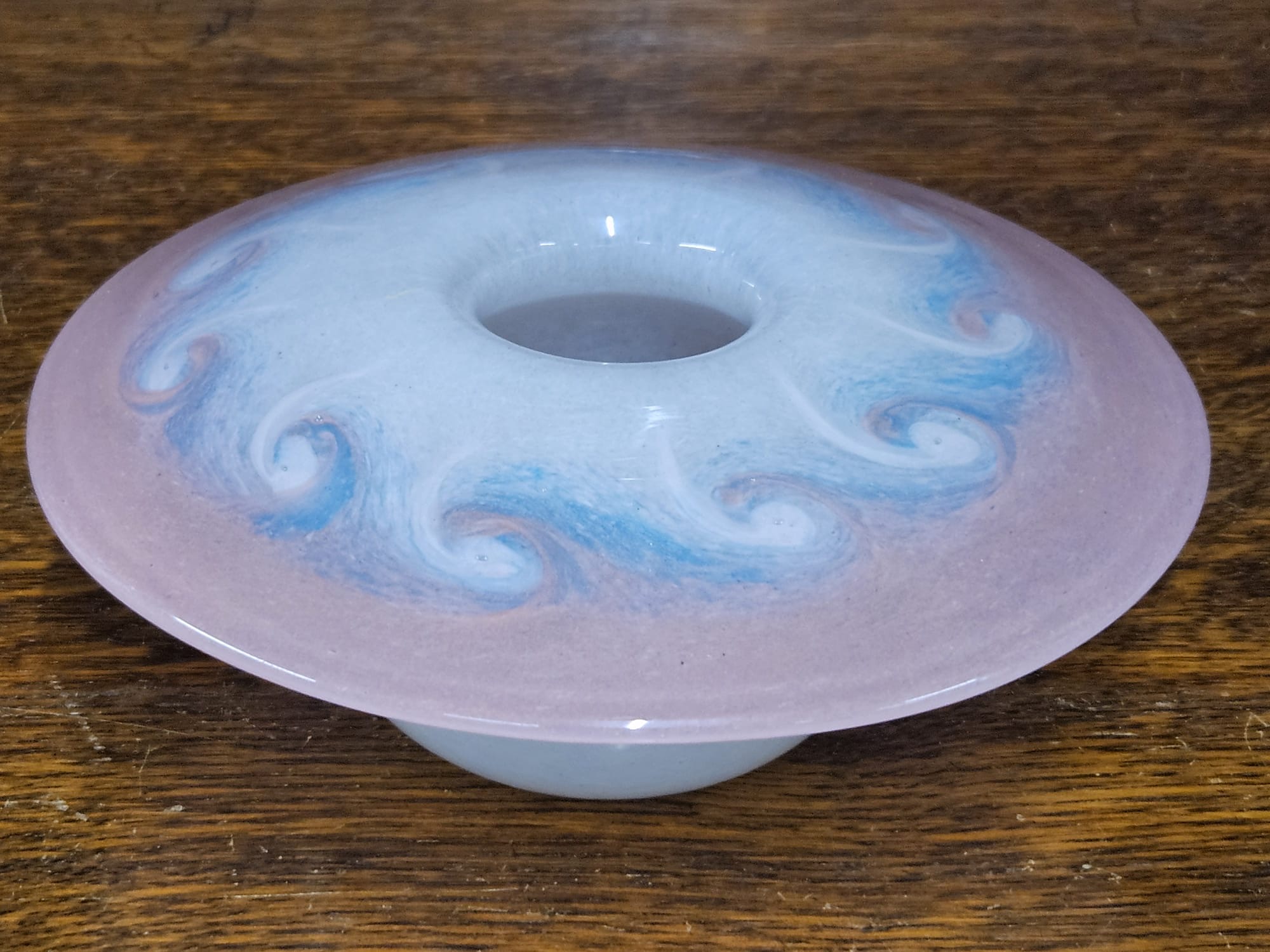 A hand-blown studio glass disc-shaped posy vase with blue and mauve swirl decoration