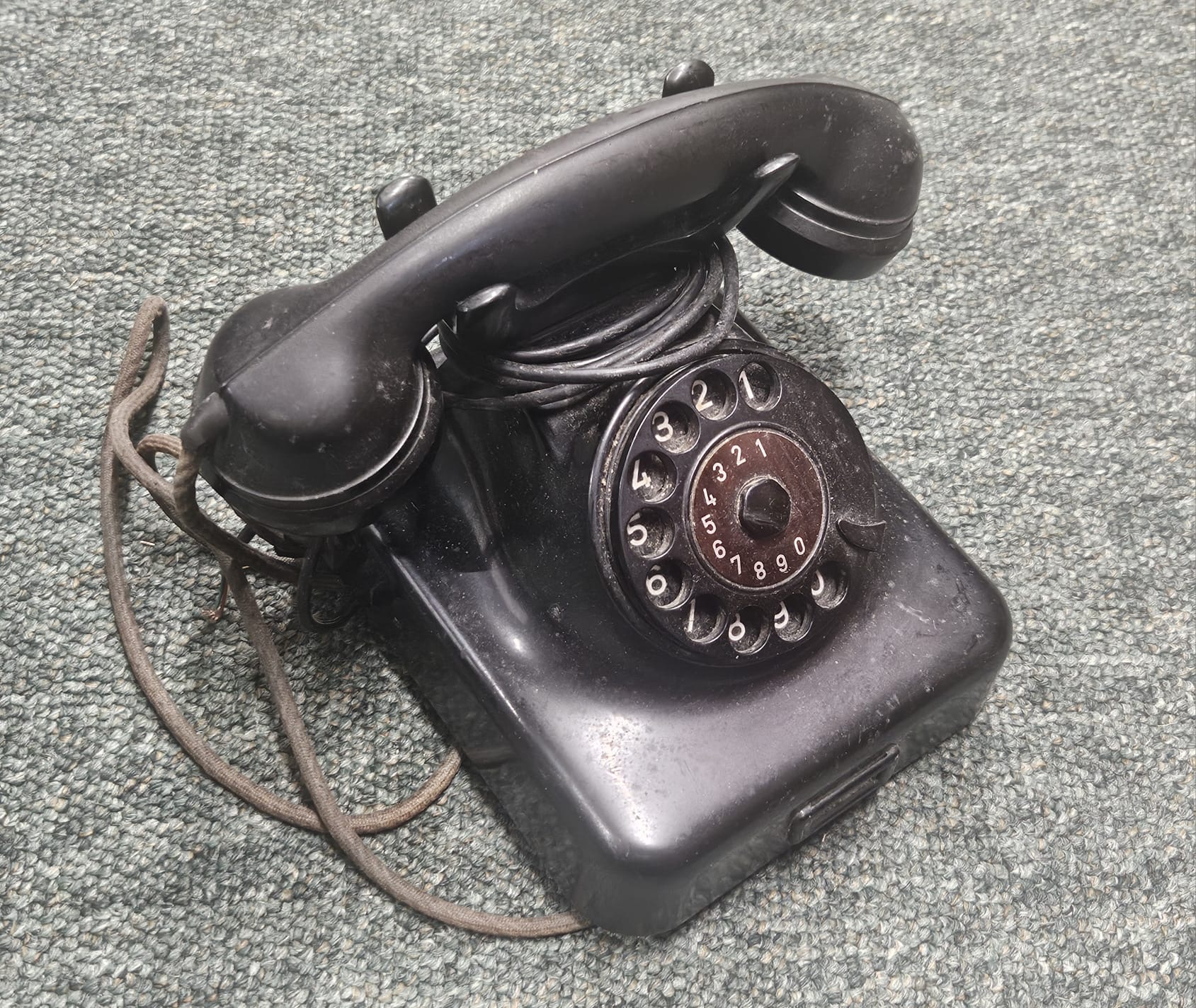 A vintage black Bakelite rotary dial telephone with directory drawer