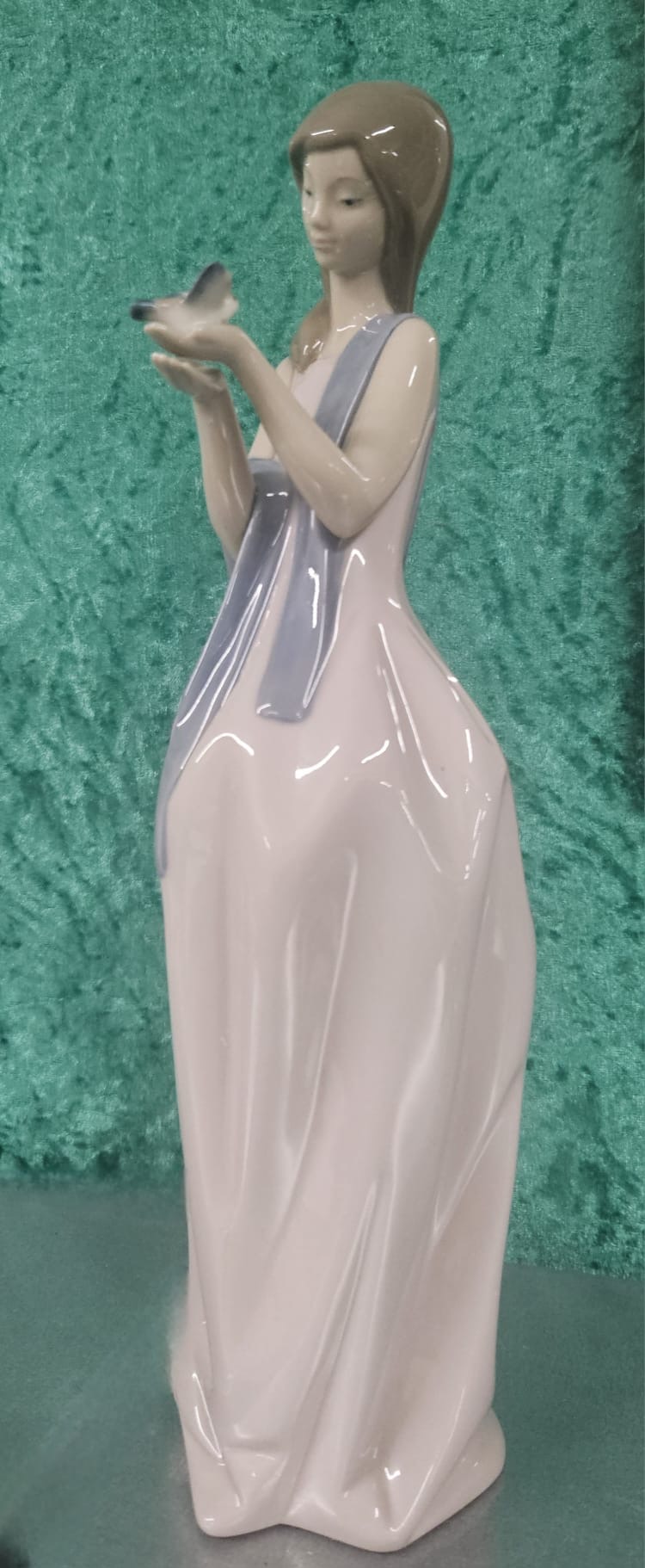 A NAO by Lladro glazed porcelain figurine of a young woman with a bird