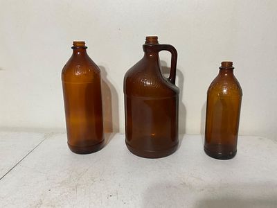 Three Amber Glass Bottles. Three amber glass bottles, including one jug-style bottle with a 