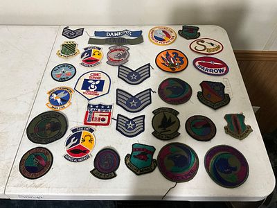 Military Patches. Over 20 military patches displayed on a table. The patches are varied 