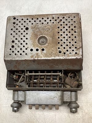 Ford Branded Vintage AM RadioÂ. A Ford-branded vintage metal AM radio unit with perforated outer