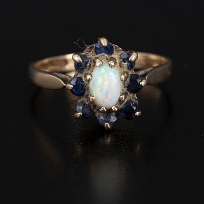 British 9K Yellow Gold, Opal and Sapphire Ring. crafted in a classic halo style, containing one 
