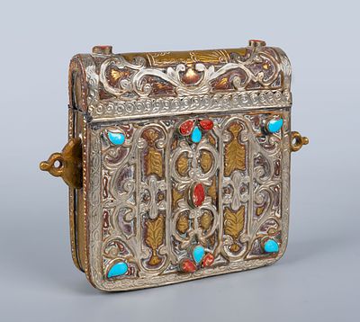 קופסה ישנה לקוראן, מתכת דו־גוונית משובצת אבנים אדומות וכחולות. עשויה מתכת זהובה המעוטרת בחריטות 