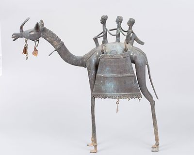 פיגורת נוי מנחושת בדמות גמל בסגנון אתני. אפריקה, בנין, המאה ה20. על גב הגמל שלוש דמויות ישובות 