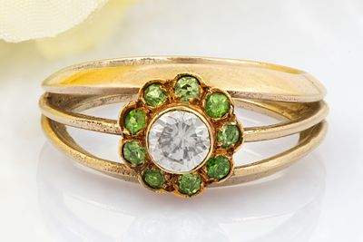 טבעת מזהב 14 קראט יהלום ואבני חן ירוקות. משובצת במרכזה ביהלום בליטוש מבריק המוקף 
בהילה של אבני 