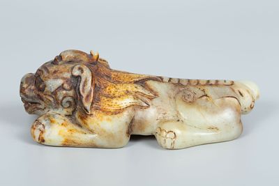 A Carved Jade Fu Dog Figurine, China. Carved jade figure of a recumbent mythical beast, in the 