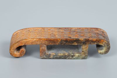 A Russet Jade Yuzhi Sword Scabbard Slide, China. Designed as a carved jade plaque forming a 