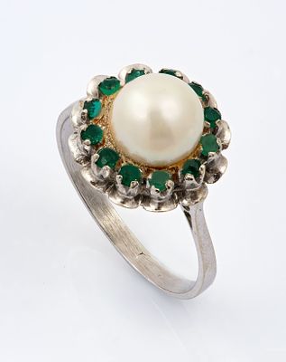 An 18K White Gold Pearl and Emerald Ring. Centered with a pearl surrounded by a halo of small 
