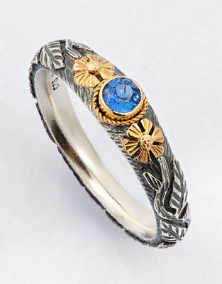 A Charming Silver and 18k Gold and Sapphire Ring. Centered with a brilliant-cut sapphire 