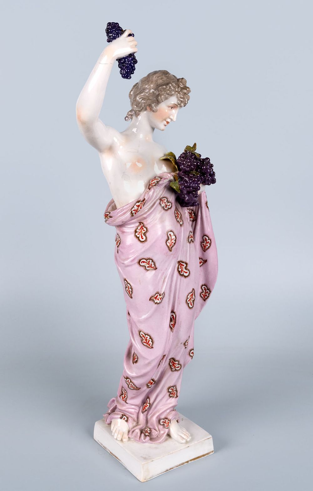 A Hochst Polychrome Porcelain Figure of a Woman Holding a Bunch of Grapes, Germany, 19th Century. 
