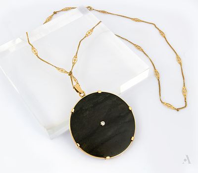 A 14K Yellow Gold Diamond and Onyx Pendant Necklace. The pendant a circular onyx plate centered 