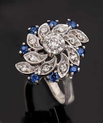 A 14K White Gold Diamond and Sapphire Cocktail Ring. Designed in a floral motif, centered by 
