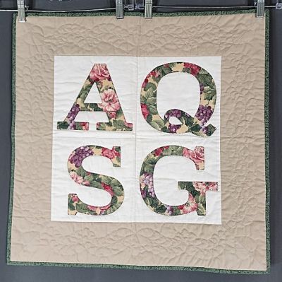 AQSG Quilt by Merry May 1993. AQSG Wall Quilt measuring 24"x24". On the back is inked: A real 