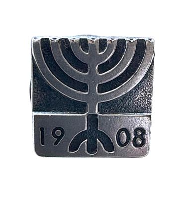 סיכת כסף ישנה עם דמות המנורה וכיתוב 1908. 
12X12 מ"מ.