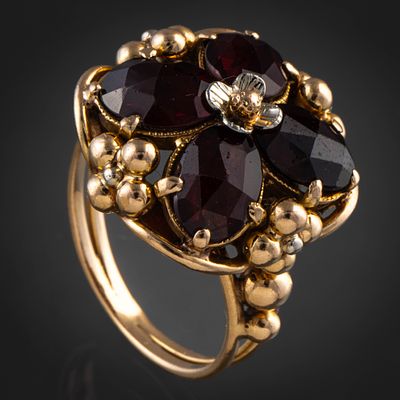 Sortija en forma de flor en oro amarillo de 18kt con cuatro granates en forma de petalos. N&uacu 