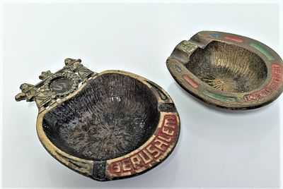 שתי מאפרות עם כיתוב ירושלים מובלט. מאפרה אחת בצורת פרסה מיוצרת בישראל וחרוט עליה HEN HOLON. 