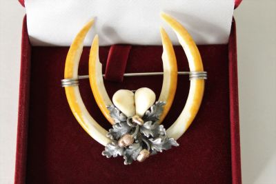 Украшение, созданное из охотничьих трофеев. 
Клык медведя и зуб ястреба. В оправе из серебра 