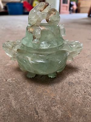 An antique hand carved green quartz lidded urn in the form of dragon heads and raised on three feet.