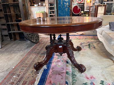 A Victorian mahogany oval tilt top table with carved legs on turned supports. 4ft long.