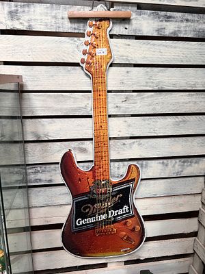 A Miller beer advertising sign pressed metal guitar. 120cm long