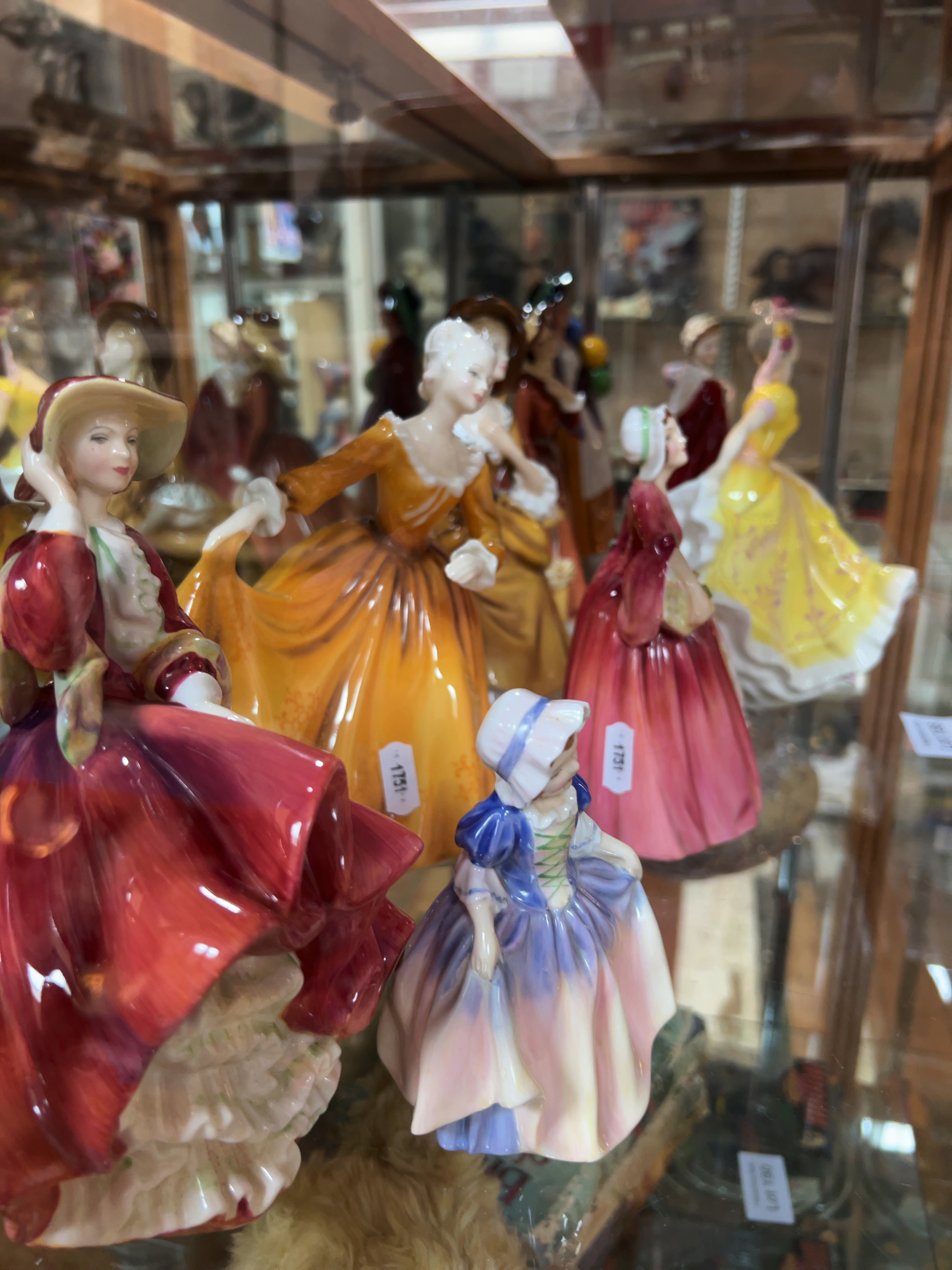 Twelve Royal Doulton Polychrome Glazed Bone China Figurines including The Old Balloon Seller and Autumn Breezes