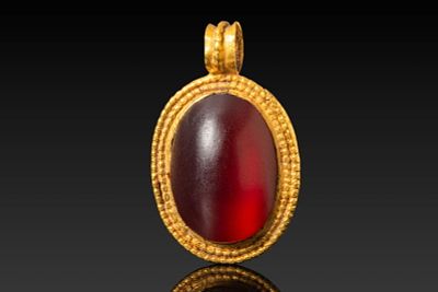 MEROVINGIAN HIGH KARAT GOLD PENDANT WITH POLISHED GLASS CABOCHON. Ca. AD 400 - 600. A 22 kt gold 