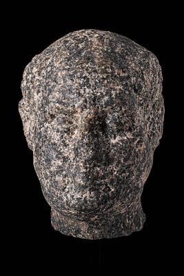 RARE EGYPTIAN GRANITE HEAD OF A MALE VOTARY. Ptolemaic Period, Ca. 200 - 30 BC. A head carved 
