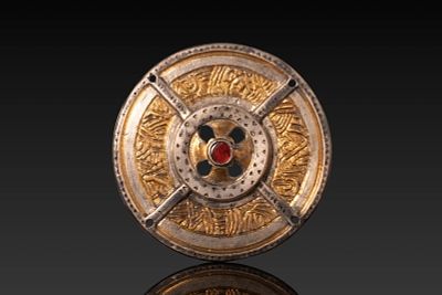 MEROVINGIAN OR SAXON SILVER-GILT APPLIQU&Eacute; WITH CENTRAL RED GARNET. Ca. AD 500 - 600. A circular 