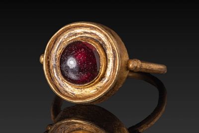 SAXON/VIKING IRON GILT RING WITH RED GARNET CABOCHON. Ca. AD 600 - 700. A gold ring with a high 