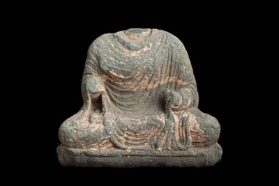 GANDHARAN STONE FRAGMENTARY FIGURE OF SEATED BUDDHA. Ca. AD 200 - 300. A carved stone fragment 