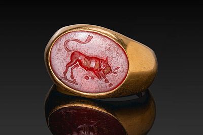 HELLENISTIC GOLD RING WITH CARNELIAN INTAGLIO OF A BULL. Ca. 100 BC. A gold ring with a broad 