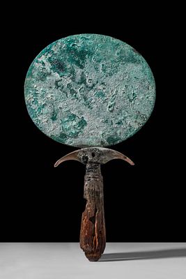 EGYPTIAN BRONZE MIRROR WITH WOODEN HANDLE. New Kingdom, Ca. 1550 - 1069 BC. A mirror composed of 