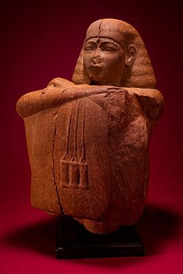 EGYPTIAN RED QUARTZITE BLOCK STATUE OF A PRIEST, POSSIBLY YUYA, PRIEST OF MIN AND FATHER OF QUEEN TI