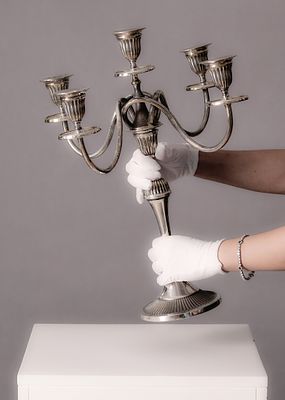 קנדלברה עשויה מתכת בגימור כסוף, עם חמש זרועות ובתי נרות תואמים. גובה: 49 ס"מ רוחב: 33 ס"מ