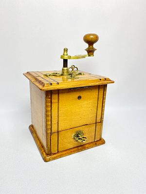Старинная кофемолка с изящными бронзовыми ручками и регулятором величины помола. Производство