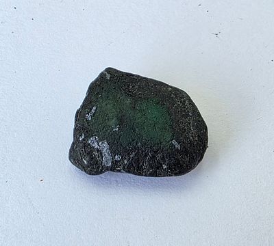 אבן אמרלד גולמית, משקל 24.4 קראט, הוצאה מבריפקה עם תג מחיר של 7$ לקראט, טבעית מהכספת 