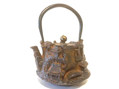 Старинный чугунный коллекционный чайник с крышкой и ручкой, и рельефным пейзажем по корпусу. 