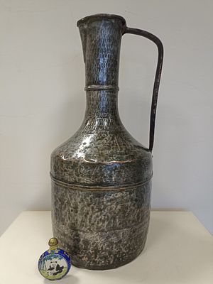 Старинный металлический кувшин с чеканкой ручной работы и декоративными чекаными элементами. 